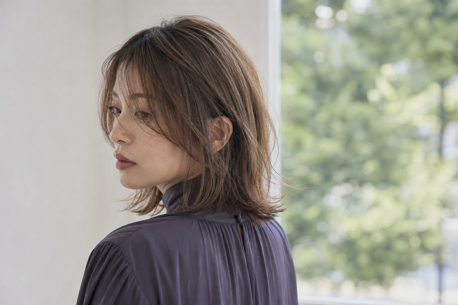 軽いシャグロブのオリーブベージュを後ろ寄りの振り向きで見せる成人女性