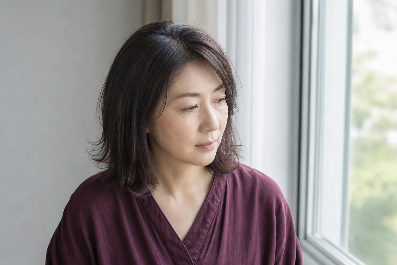肩ロブの中心から少しずれた柔らかな分け目をやや上から見せる成人女性