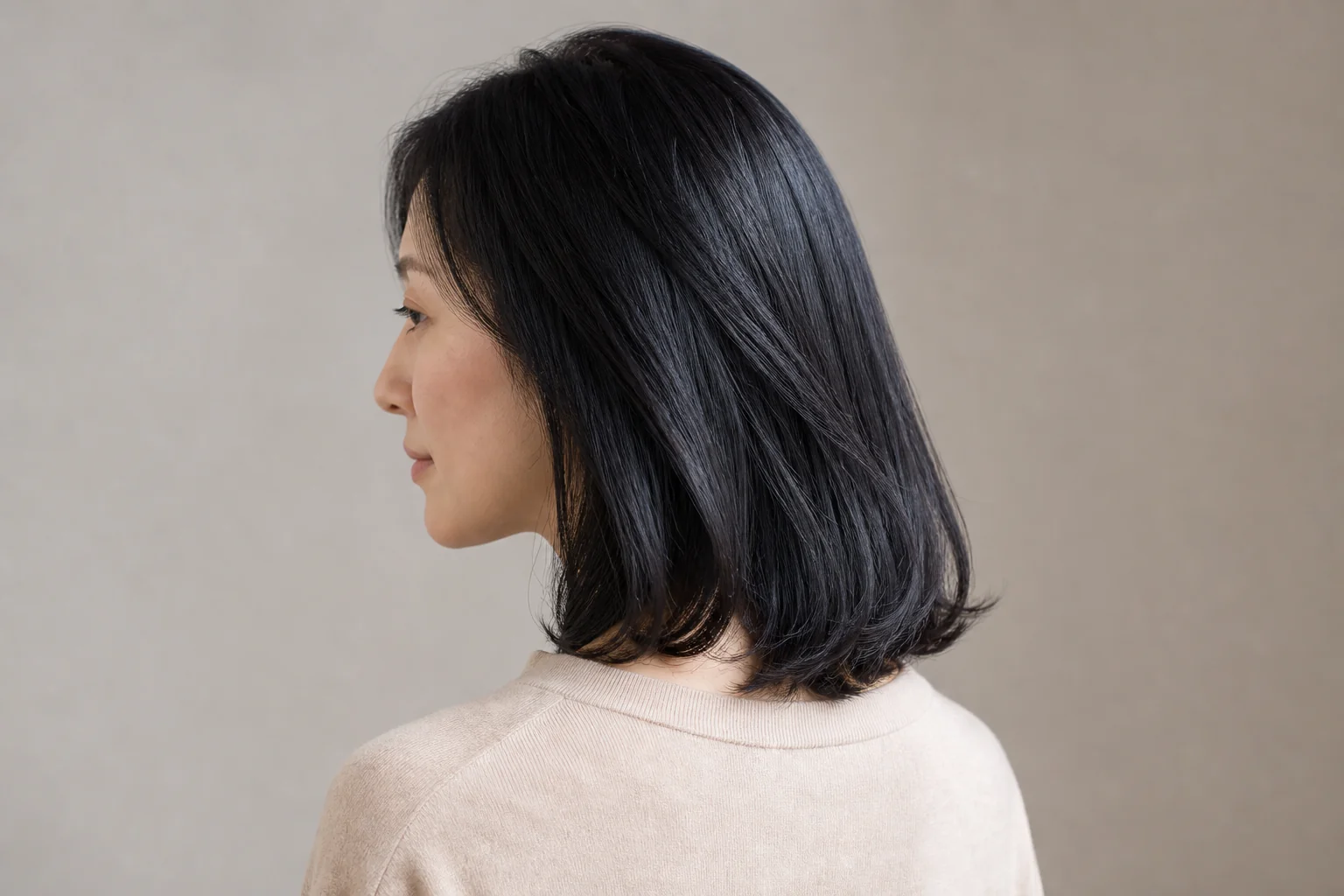 黒髪に近い髪へ深い青のつやが見える鎖骨丈のロブ