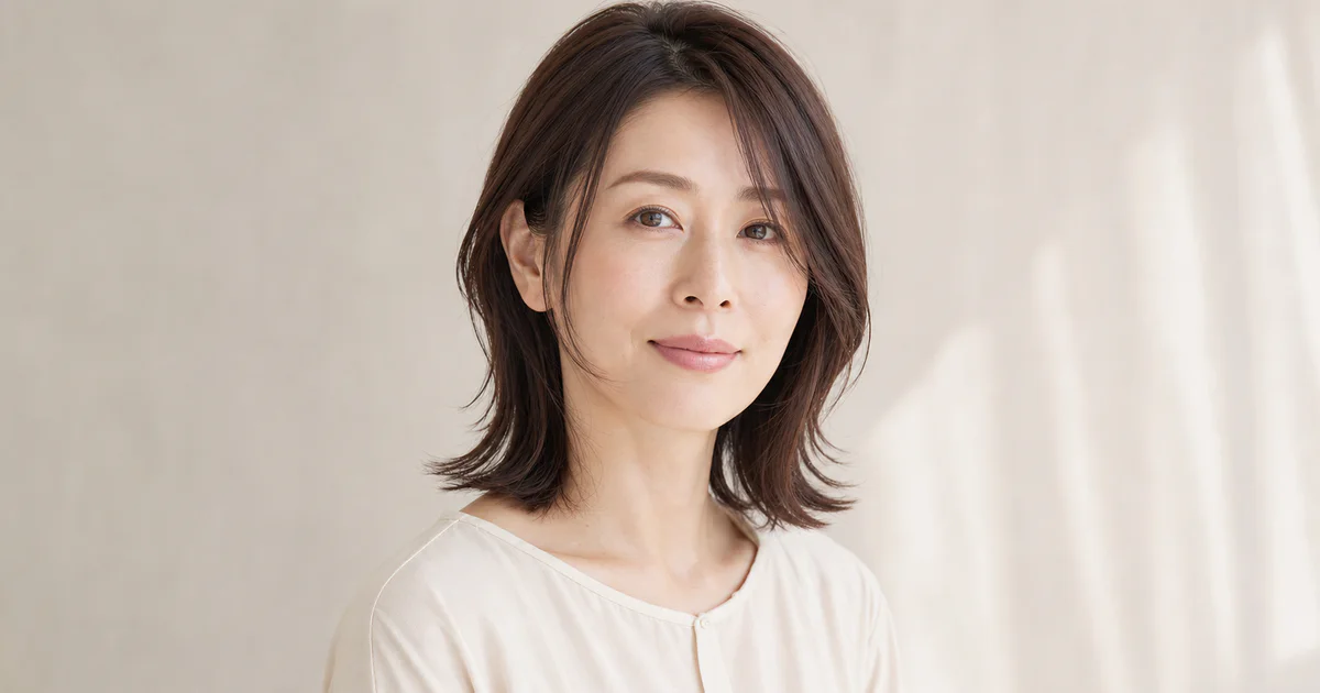 頬骨に沿う顔まわりレイヤーのダークブラウンヘアを見せる成人女性