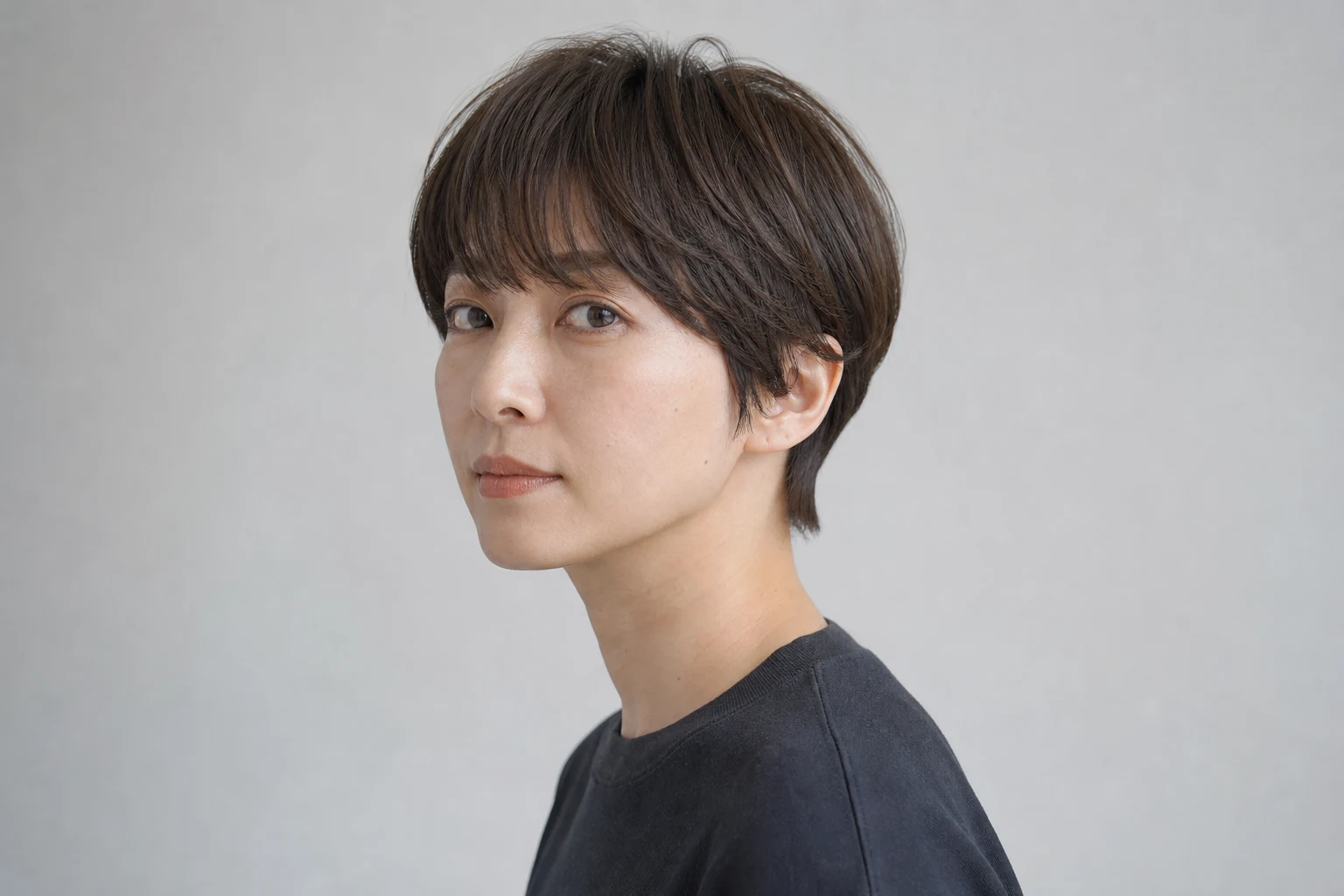 丸いトップとタイトな襟足を組み合わせたコンパクトマッシュショートの成人