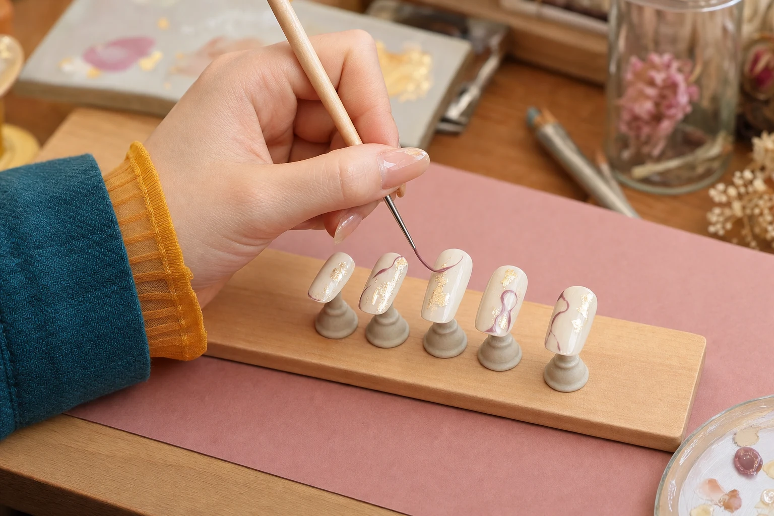 スタンドへ固定した5枚のネイルチップへ細筆で模様を描く手元