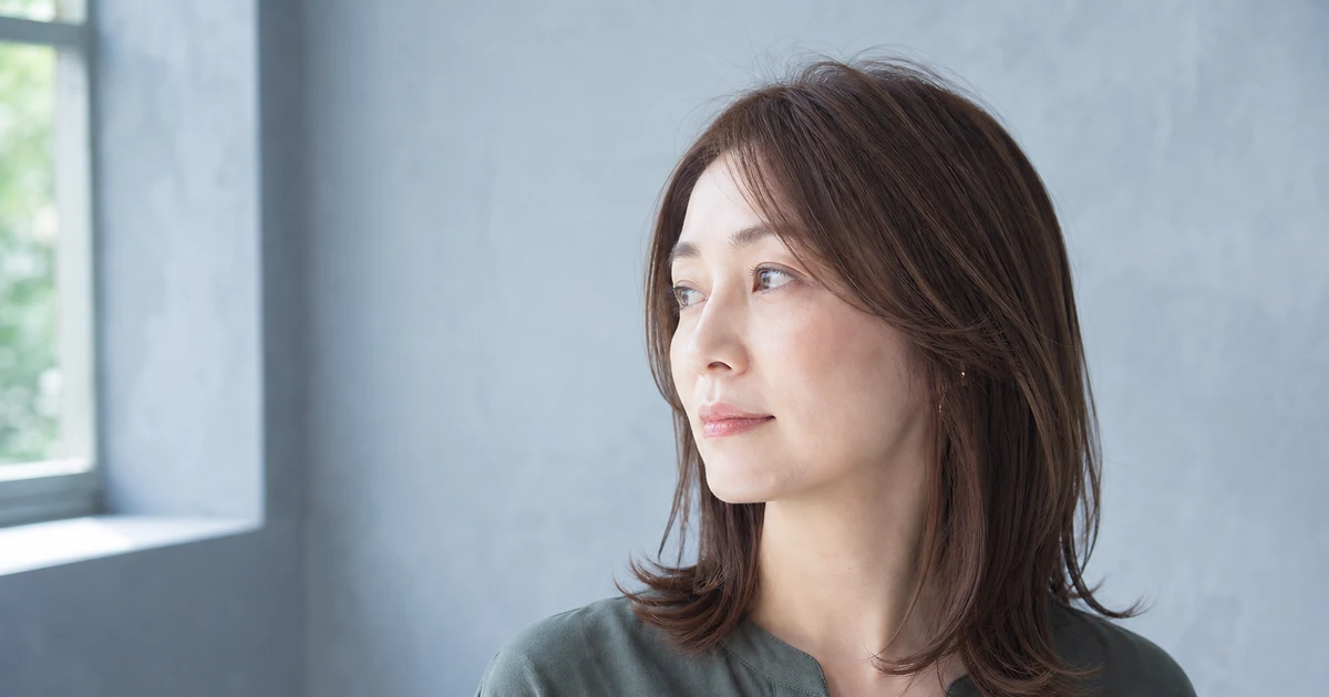 鎖骨レイヤーの明るめブラウンを左前方から自然光で見せる成人女性
