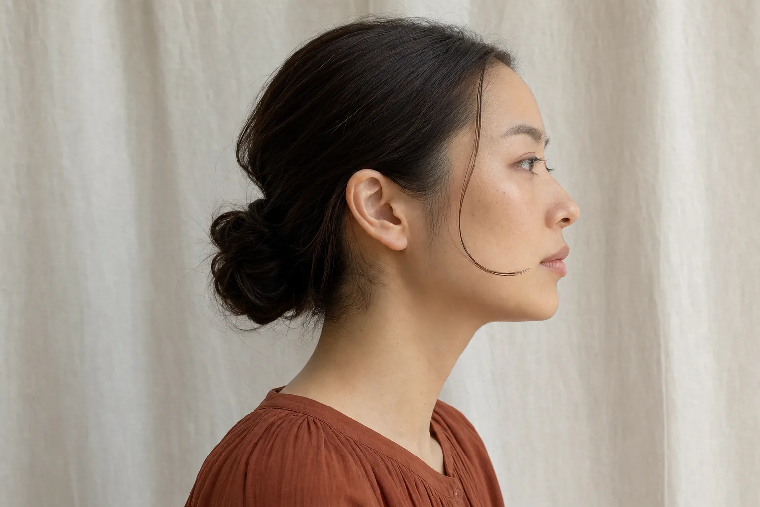 右横顔で細い顔まわり毛束が口角付近で終わりあごまで肌が見える成人女性