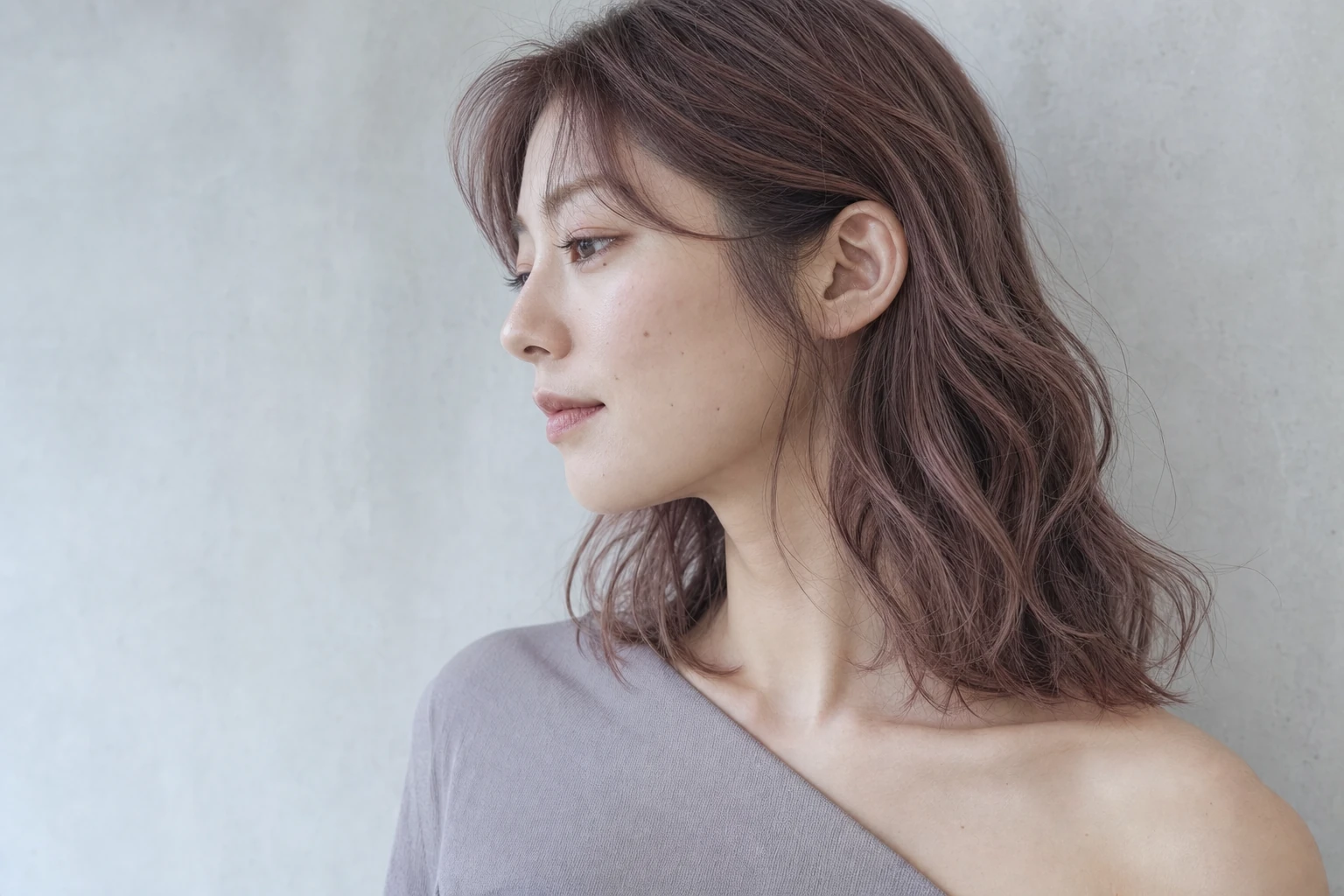 肩のソフトウェーブのモーヴピンクを近い左横顔で見せる成人女性