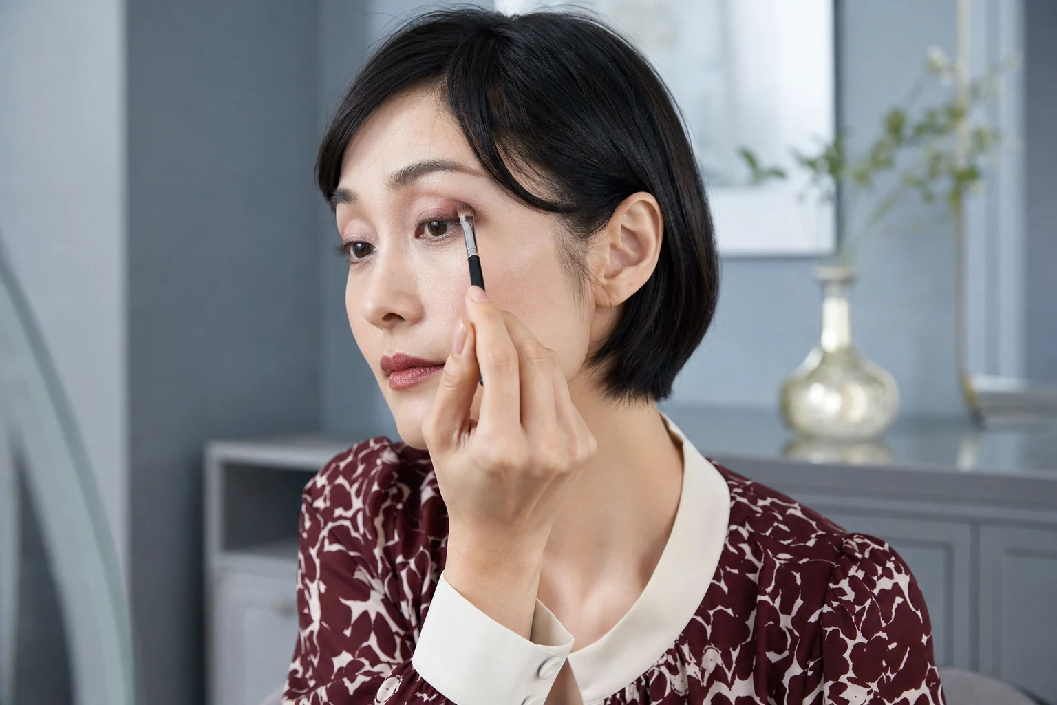 目の際からくぼみ方向へローズブラウンのアイシャドウをぼかす成人女性