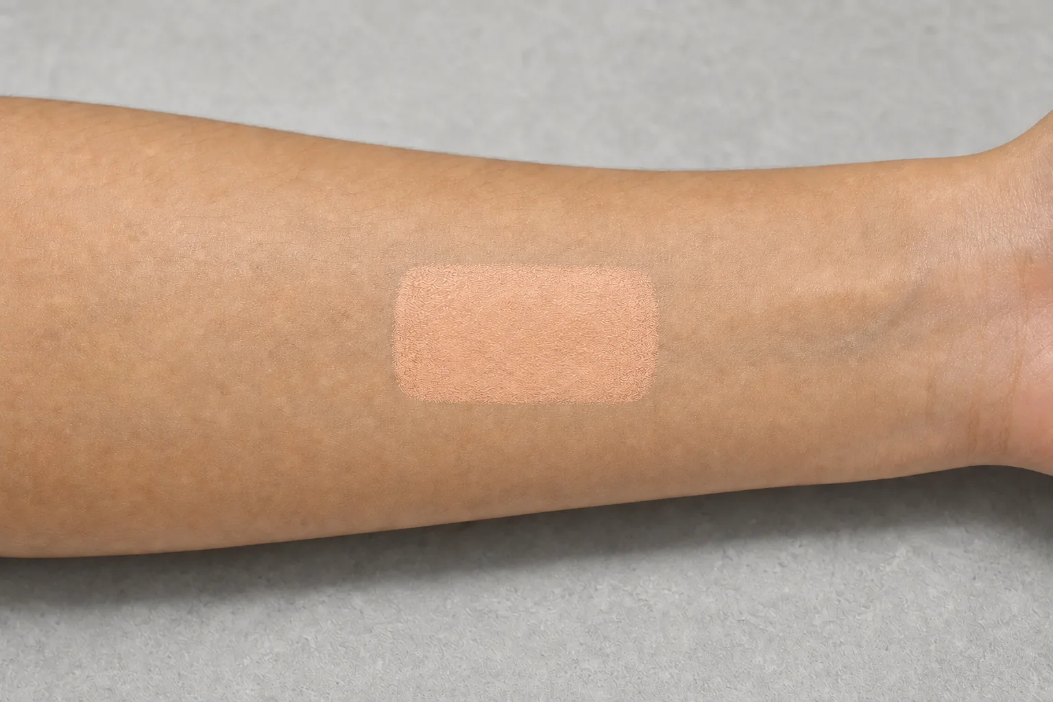 前腕に塗った明るいサーモンピーチベージュのスウォッチ