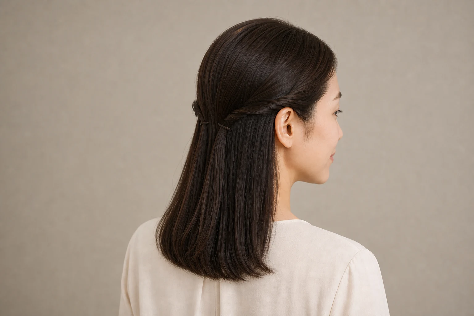 暗いストレートヘアのこめかみ付近を左右別にねじり小さなピンで留めたハーフツイン