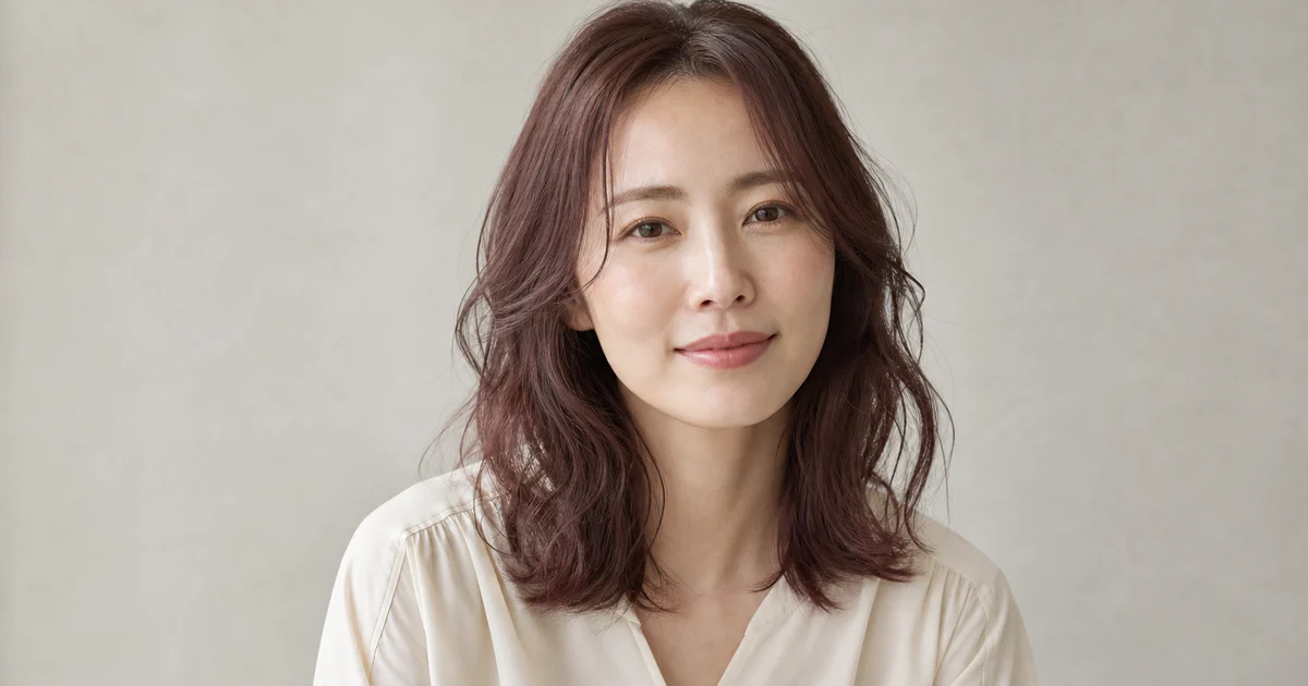 落ち着いたピンクブラウンのミディアムヘアを自然光で見せる成人女性