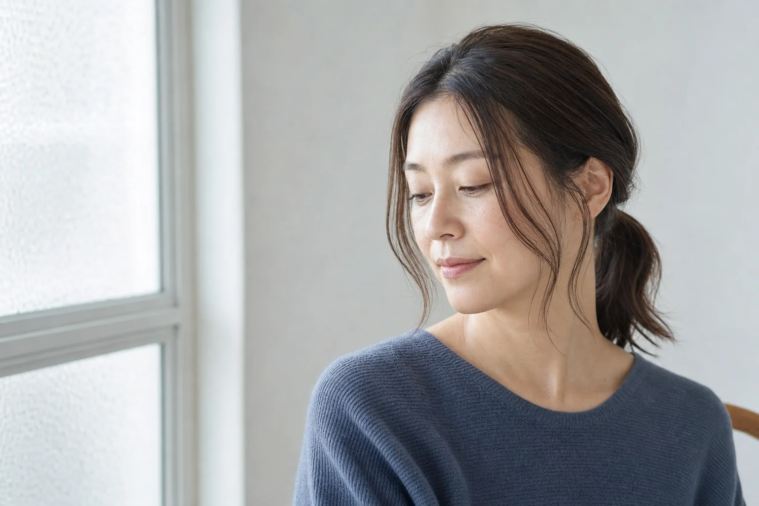 低いひとつ結びと細い顔まわり毛束を組み合わせた成人女性
