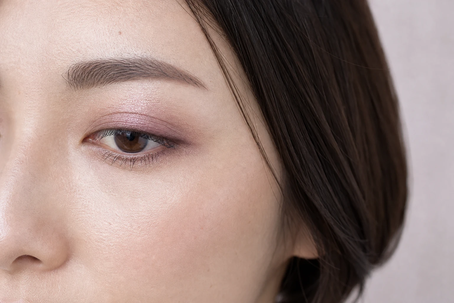 左目に淡いラベンダーとくすみピンクブラウンを重ねたボブヘアの成人女性