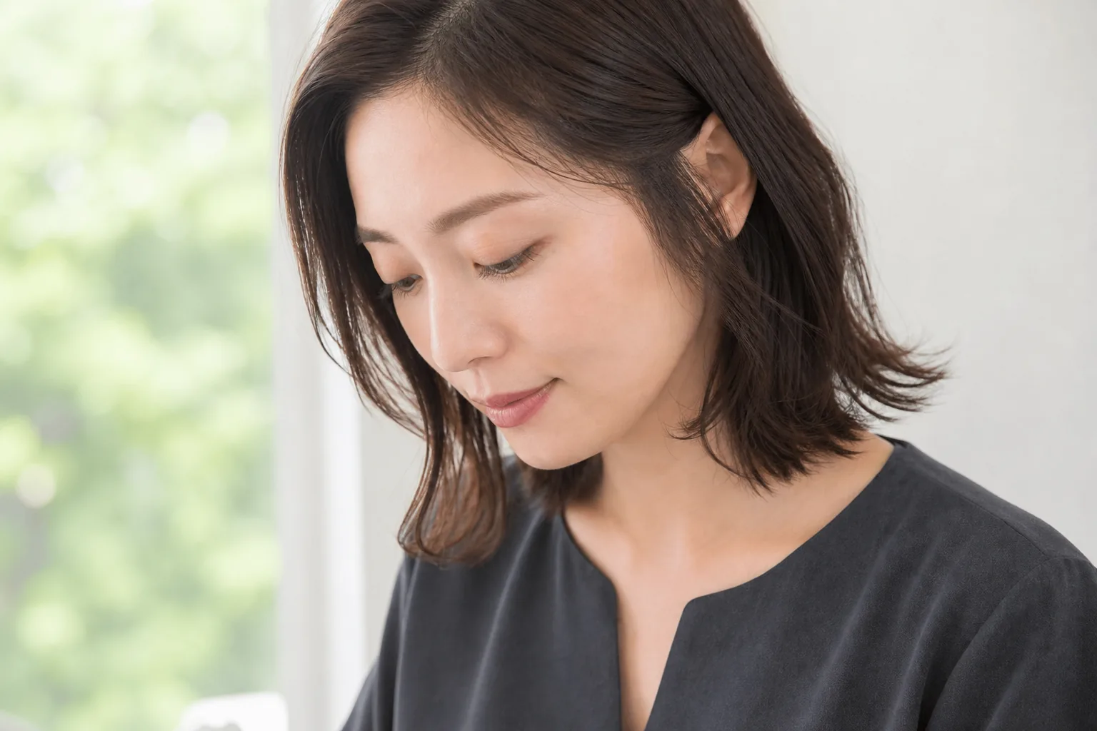 こめかみの短い毛から頬とあごへ細くつながるレイヤーロブの成人女性