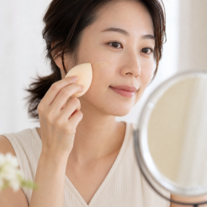 リキッドファンデーションを手の甲に少量取りスポンジで頬へなじませる様子