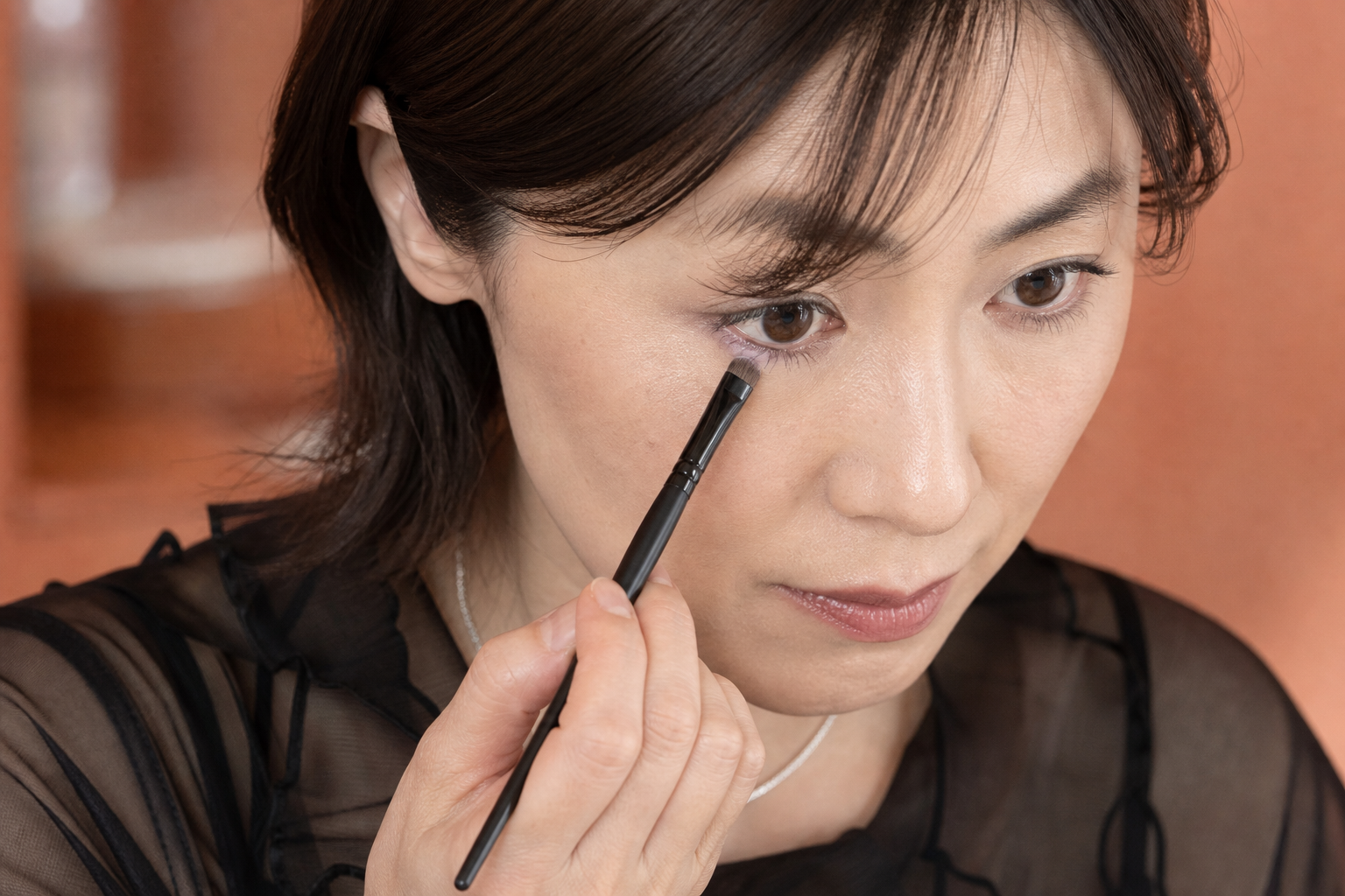 下まぶた中央へ淡いラベンダーを細いブラシでのせる40代女性