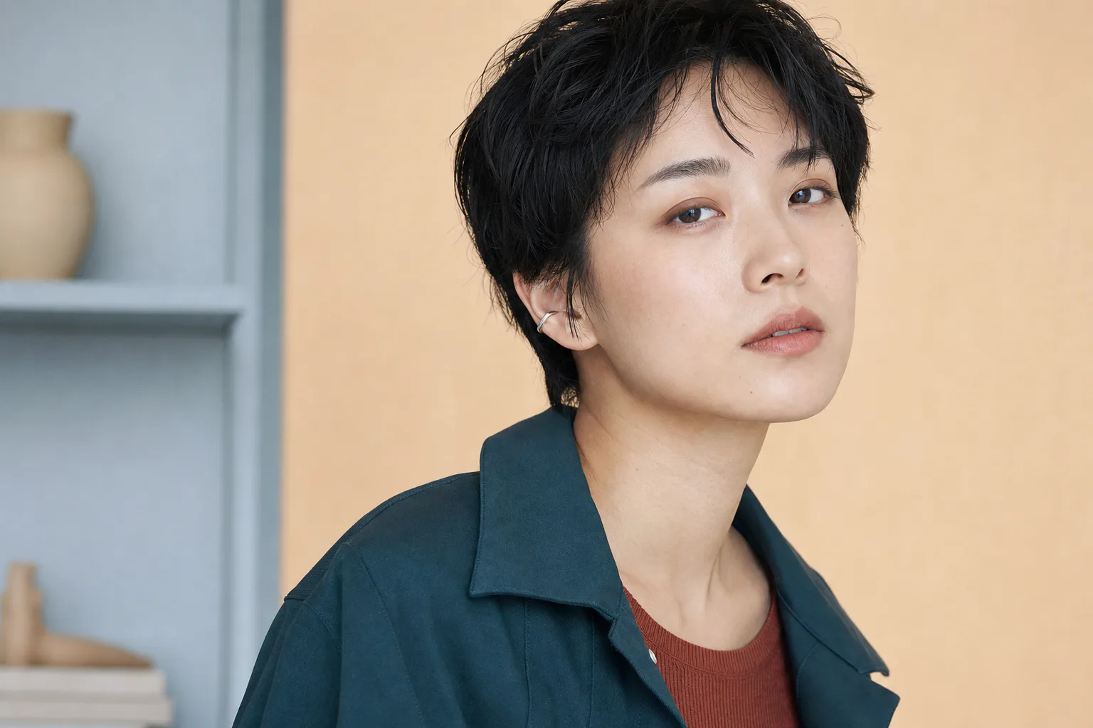 短い黒髪と自然な直線眉、低彩度の目元とローズベージュの唇に仕上げた成人
