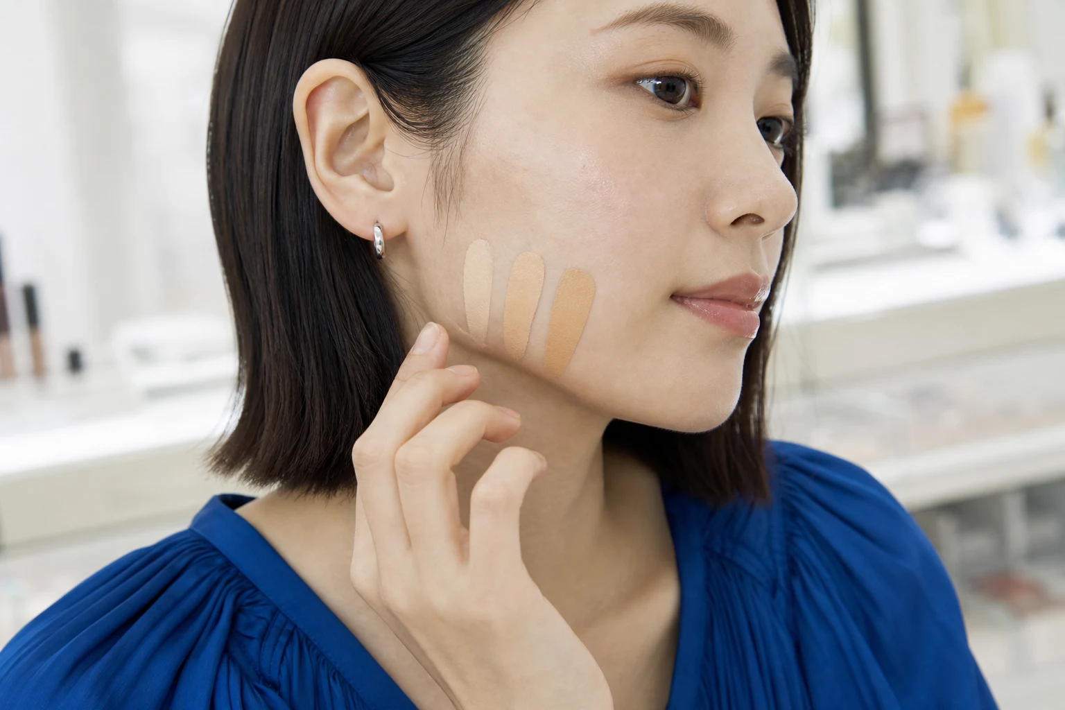 フェイスラインへ明るさと色調の異なる3色を置いた20代後半の女性