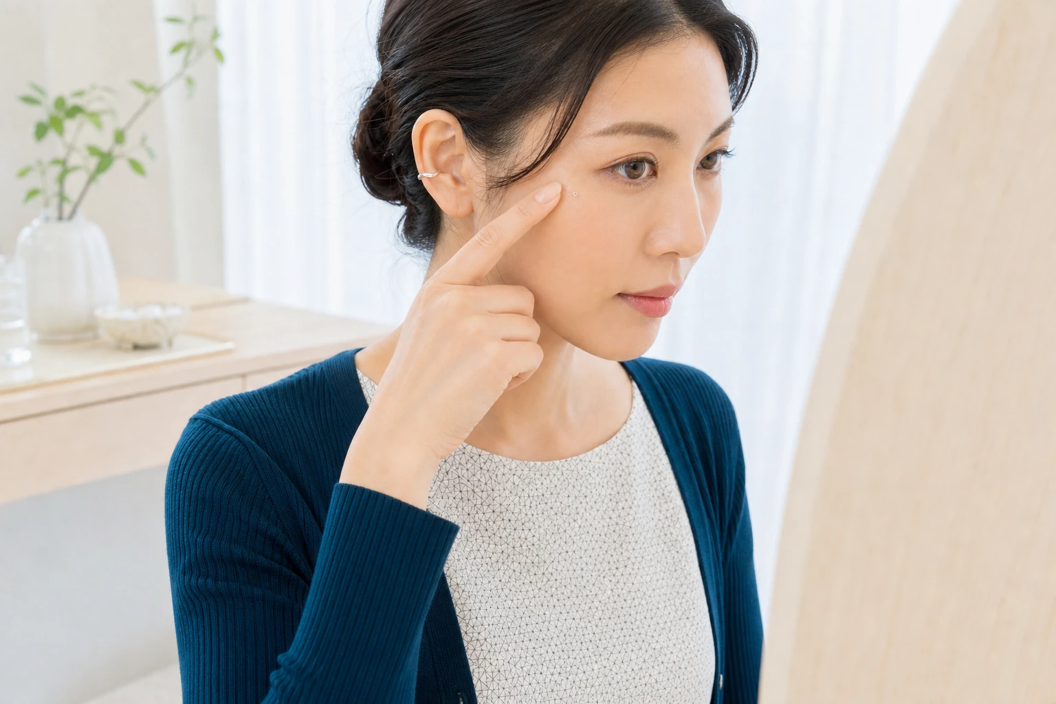 貼付後に指の腹で頬骨上のラインストーンを軽く押さえ、目を開けて違和感を確かめる30代の成人女性