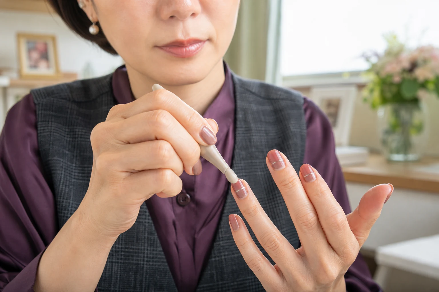 シリコンツールでネイルテープの中央から端を密着させる40代女性