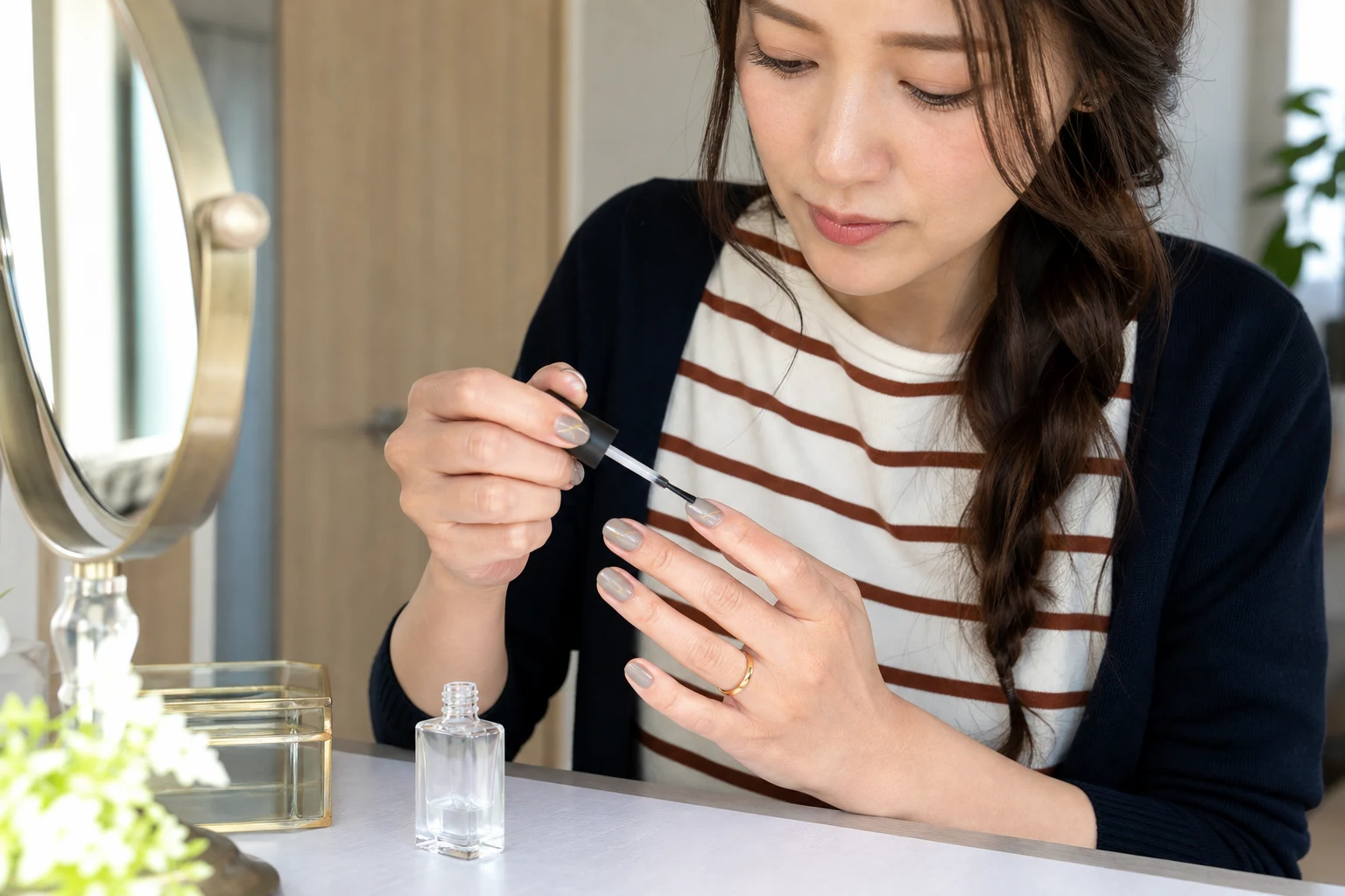 密着させたネイルテープの上へトップコートを軽く塗る30代女性