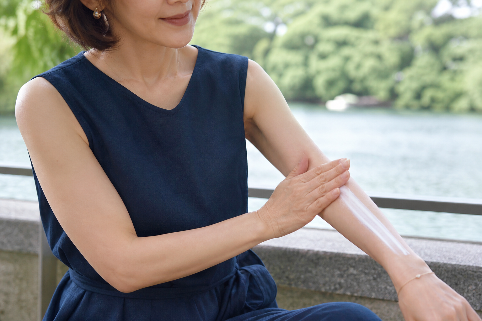 公園で腕に線状の日焼け止めを出している女性